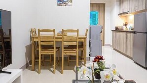 A modern apartment with a dining area, kitchen, and a living space with a TV and a plant. - Family 2BR at MOA Sea Residence Sleeps 5 (Pasay City)