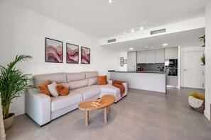 A modern living room with a sofa, coffee table, and artwork on the wall. - LXR Higueron Privé 2-Bedroom Stays (Fuengirola)