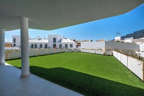 A rooftop with artificial grass, white columns, and modern buildings in the background. - LXR Higueron Privé 2-Bedroom Stays (Fuengirola)
