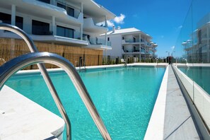 A modern hotel with a swimming pool, multiple balconies, and a clear blue sky. - LXR Higueron Privé 2-Bedroom Stays (Fuengirola)