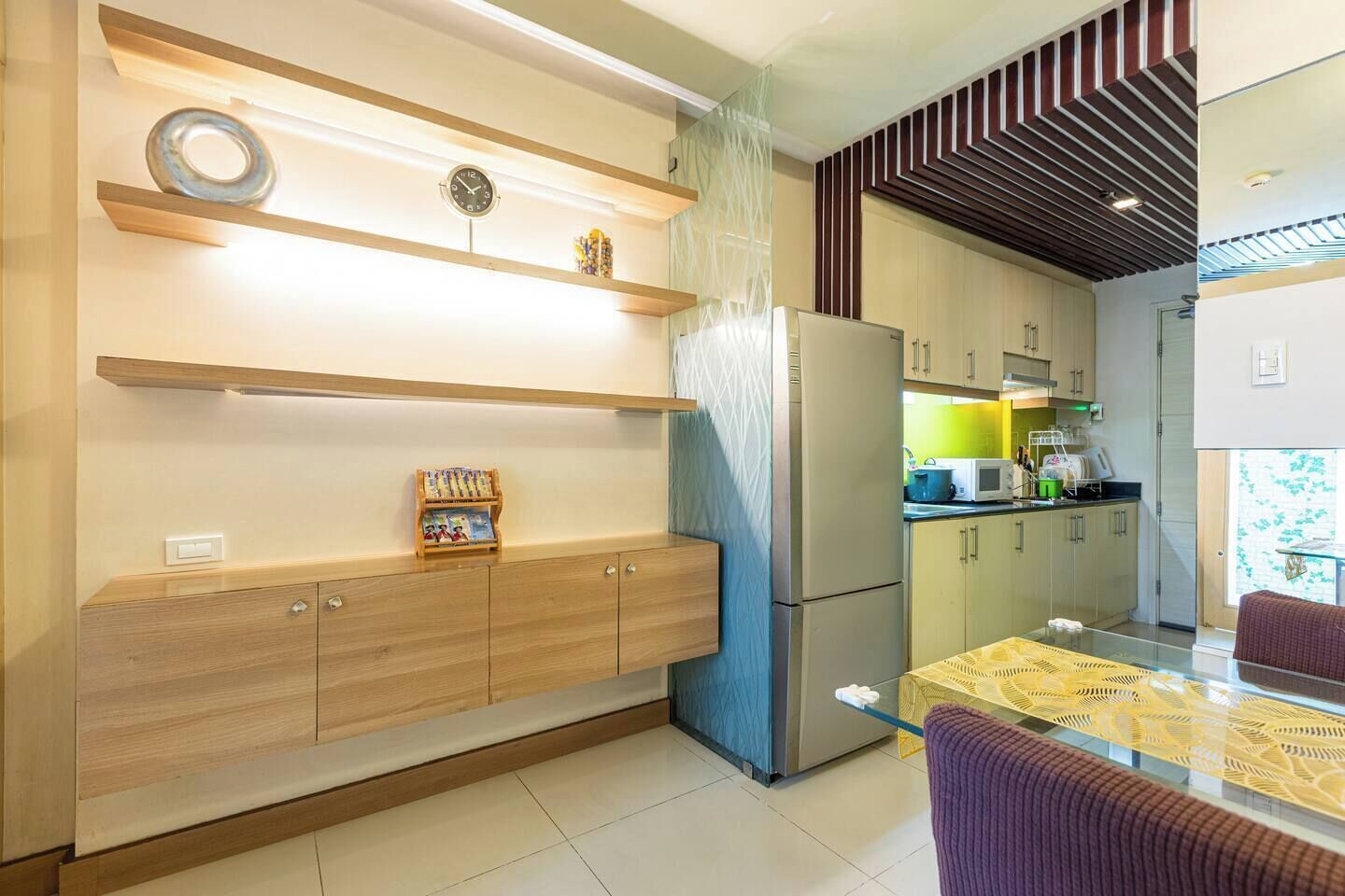 A modern kitchen with built-in appliances, wooden cabinetry, and a glass dining table.