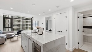 Una cocina moderna con una isla de mármol, estanterías empotradas y un comedor con sofá y mesa de centro.