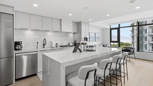 Una cocina moderna con encimera de mármol, electrodomésticos de acero inoxidable y una isla grande con taburetes de bar.