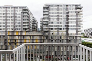 Een modern meerlaags gebouw met een glazen gevel, meerdere balkons en een commercieel gedeelte op de begane grond met signage.