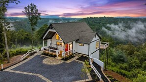 Une maison dotée d’un porche, d’un espace couvert et offrant une vue sur un paysage boisé.