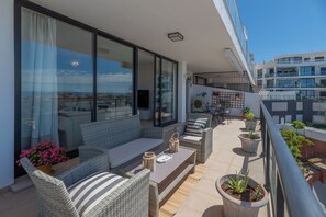 Ein Balkon mit Gartenmöbeln, Blumentöpfen und Blick auf die Stadtlandschaft.