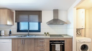A modern kitchen with wooden cabinets, a built-in oven, a dishwasher, a sink, and a washing machine. - LXR Hollywood Hills 2-Bedroom: Stunning Views (Mijas)