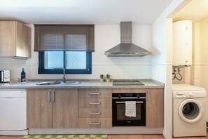 Eine moderne Küche mit Holzschränken, Backofen, Geschirrspüler, Spüle und Waschmaschine.