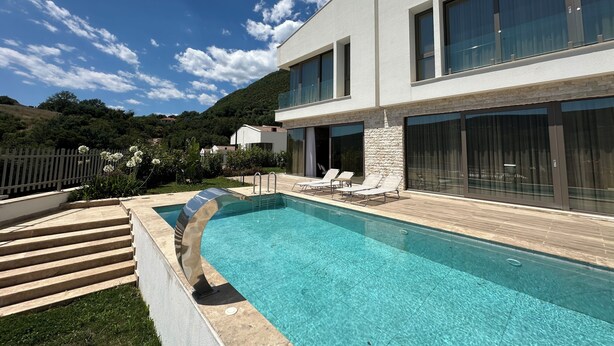 Uma casa moderna com piscina, janelas amplas e uma parede de pedra.