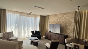 Uma sala de estar moderna com sofá, poltrona, mesa de jantar e televisão.