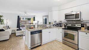 A modern kitchen with white cabinets, stainless steel appliances, and a granite countertop. - Black & White Oasis+ heated pool, close to Siesta (Sarasota)