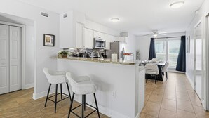 A modern kitchen with white cabinets, a microwave, and a dining area with a table and chairs. - Black & White Oasis+ heated pool, close to Siesta (Sarasota)