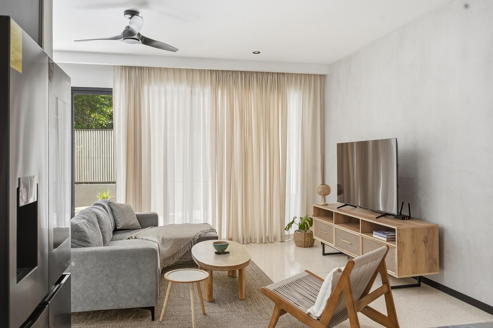 Ein modernes Wohnzimmer mit einer Couch, einem Couchtisch, einer TV-Konsole und einem Deckenventilator.