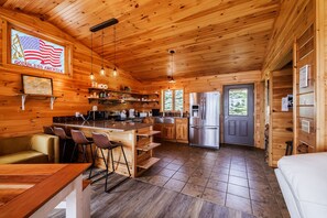 A wooden cabin interior with a kitchen, dining area, and a bar. - Bella Vista  50 Acres, Pond, Hot Tub & Game Room (Dalton)
