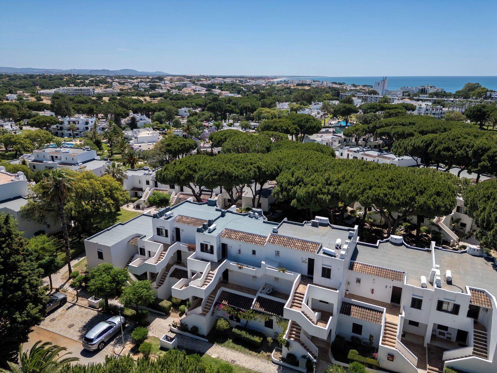 Ein Küstenwohngebiet mit weißen Gebäuden, blauem Himmel und Blick auf das Meer.