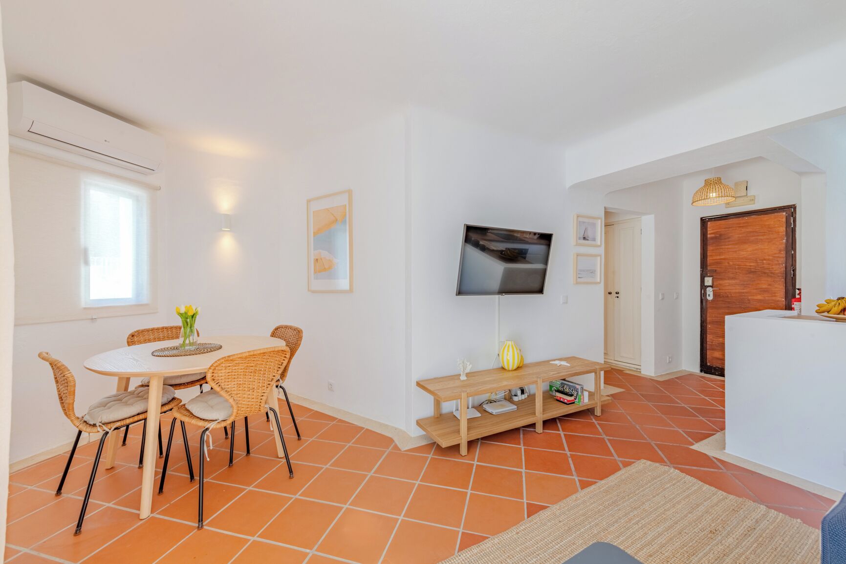 Un salon comprenant une table à manger, des chaises, un téléviseur et un banc en bois.