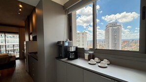 Eine moderne Küche mit Kaffeemaschine, Tassen und Blick auf die Stadtlandschaft.