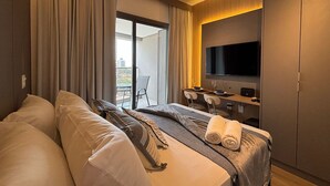 Ein Hotelzimmer mit Bett, Schreibtisch mit Fernseher und einem Balkon.