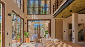 Un intérieur spacieux avec une longue table en bois, un fauteuil suspendu et un balcon offrant une vue imprenable.