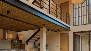Un intérieur spacieux avec un plafond haut, une mezzanine et un coin repas doté de tables et de bancs en bois.