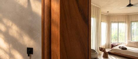 Une salle de bain moderne avec une douche, une porte en bois et une vue sur une chambre à coucher avec un lit et des rideaux.