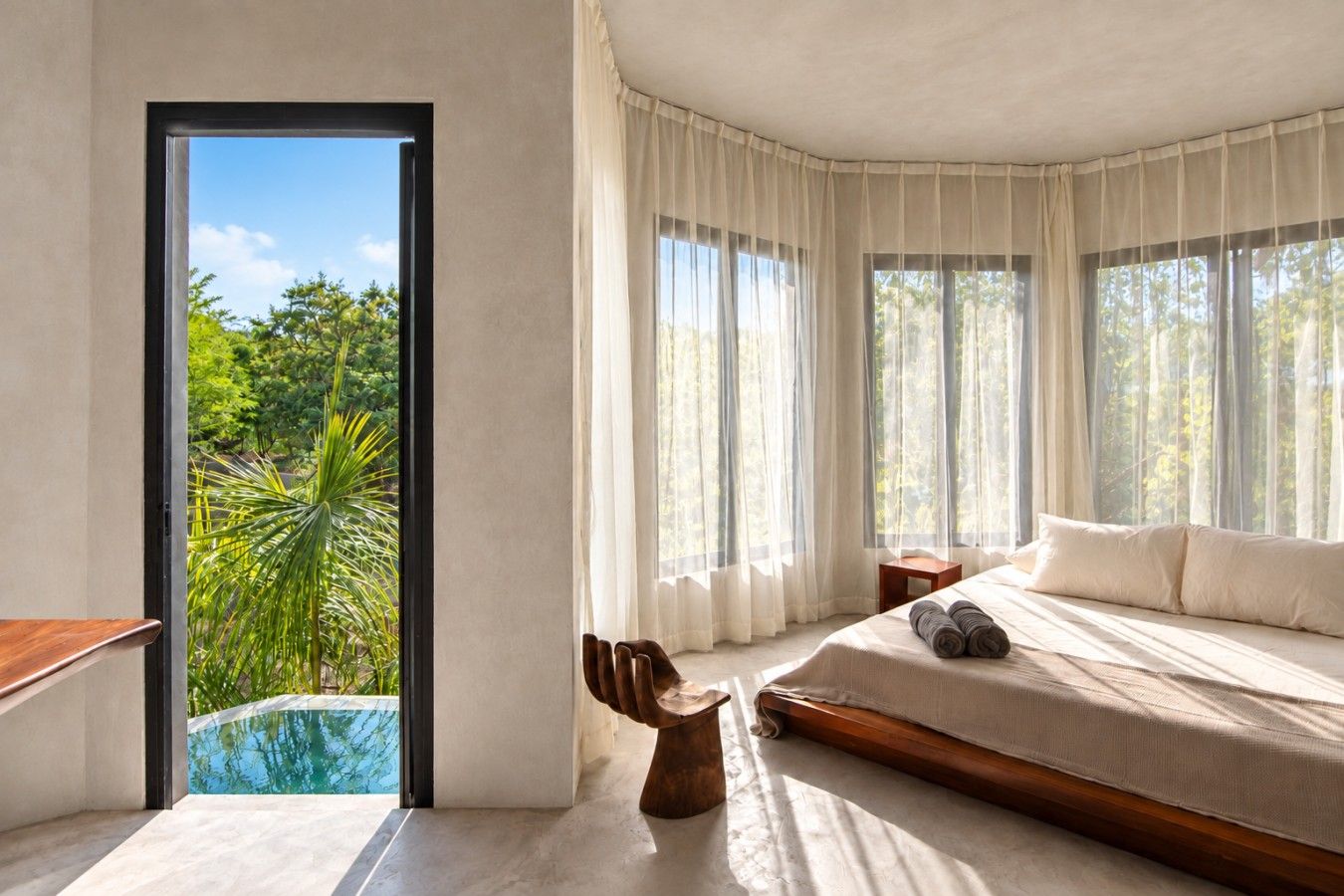A bedroom with a large bed, a view of a swimming pool, and a door leading outside.
