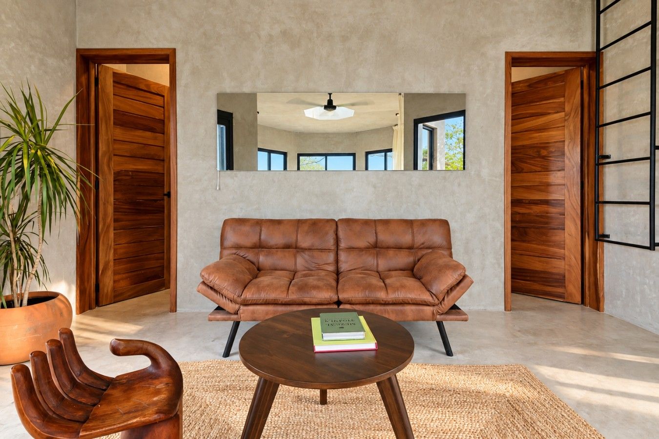 A modern living room with a leather sofa, a round coffee table, and a potted plant.