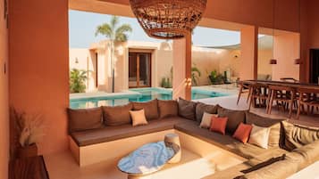Una sala de estar moderna con piscina, un sofá, una zona de comedor y una lámpara colgante.
