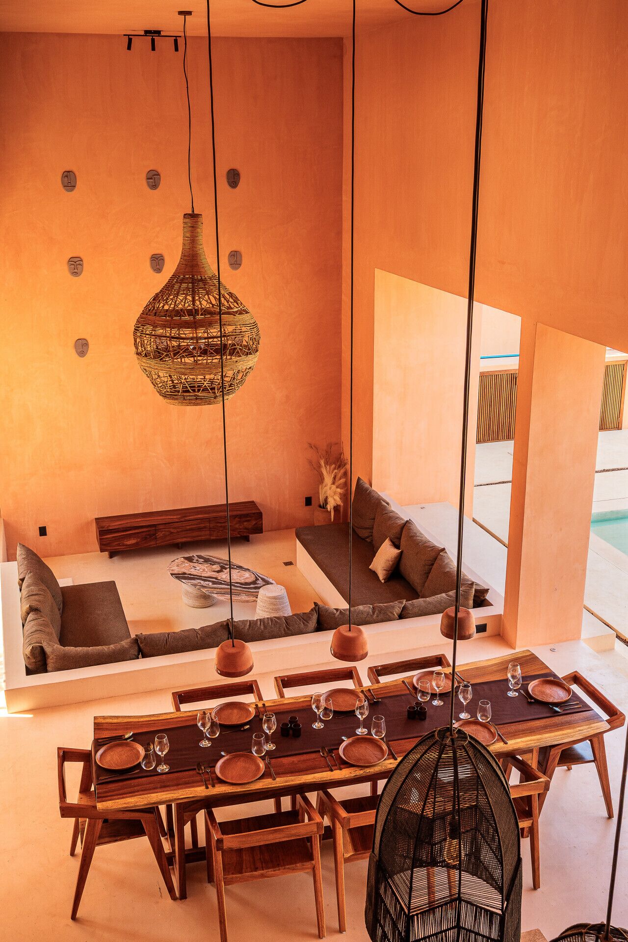 Un interior moderno con zona de comedor, sofá y lámparas colgantes.