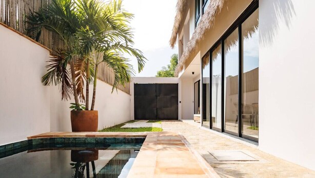 A modern building with a pool, large windows, and a potted palm tree. - Alberca privada, starlink, AC, a 5 min de la punta (Puerto Escondido)
