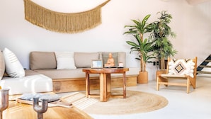 A modern living room with a sofa, a wooden coffee table, a hanging macrame, and a potted plant. - Alberca privada, starlink, AC, a 5 min de la punta (Puerto Escondido)