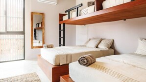 A bedroom with two beds, a wooden shelf, a mirror, and an air conditioning unit. - Alberca privada, starlink, AC, a 5 min de la punta (Puerto Escondido)