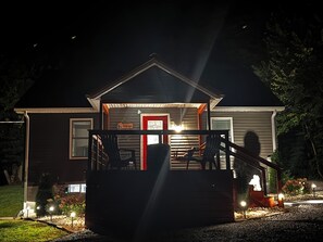 Una casa con porche, una puerta roja y una escalera que lleva a la entrada.