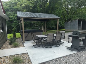 Un patio al aire libre con una parrilla, mesa y sillas.