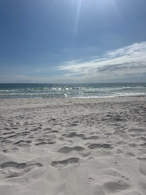 Ein Strand mit Fußabdrücken im Sand und dem Meer im Hintergrund.