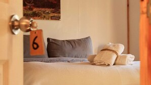 Una cama bien hecha con una almohada, una toalla y un cartel con el número 6 en la pared.