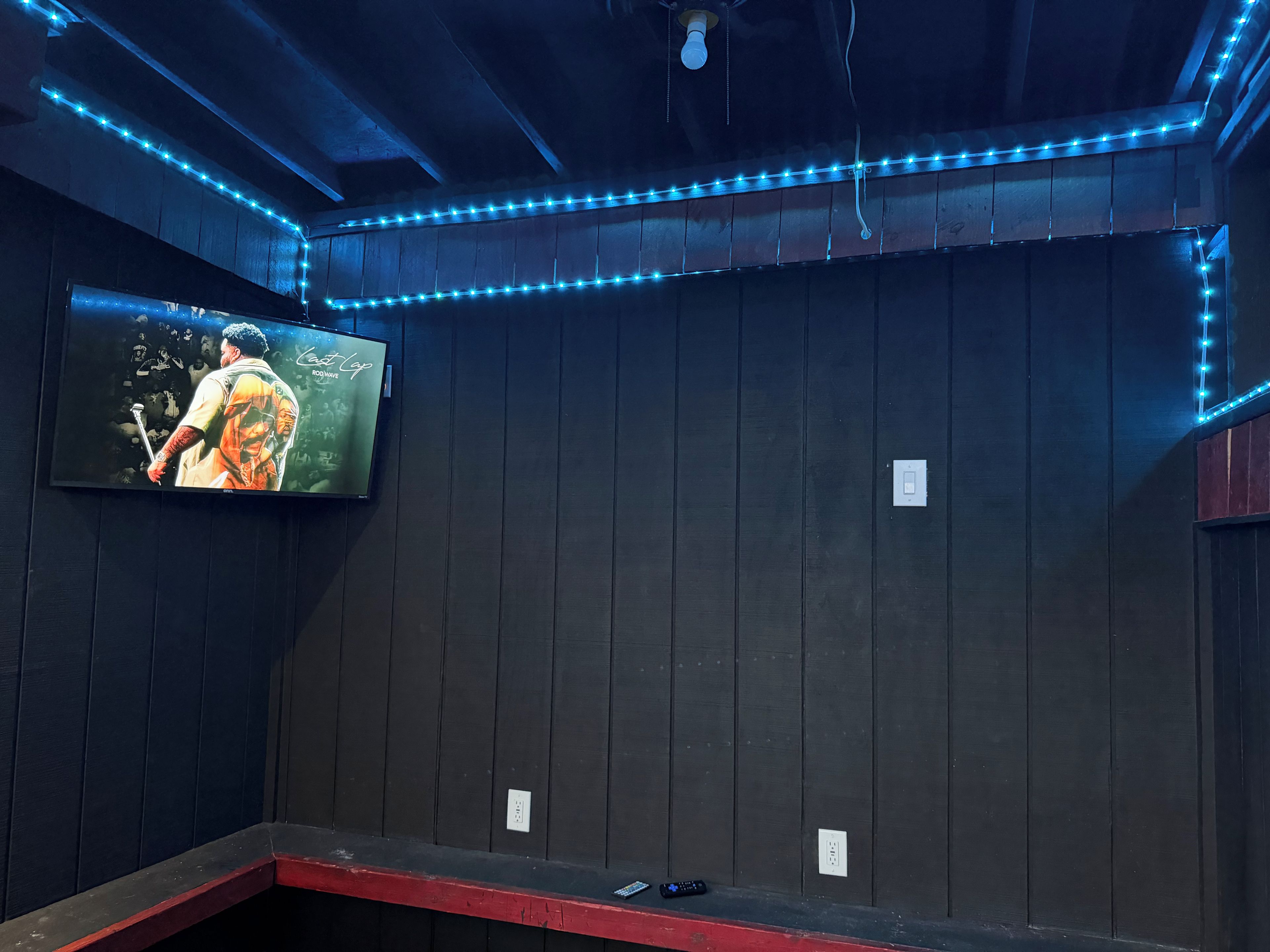 Une pièce dotée d’un téléviseur fixé au mur, d’un ventilateur de plafond et d’éclairage à diodes électroluminescentes bleues.