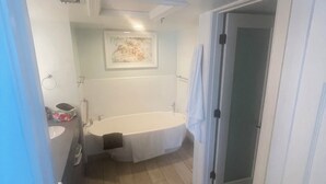 Ein Badezimmer mit Badewanne, Waschbecken und einem gerahmten Bild an der Wand.