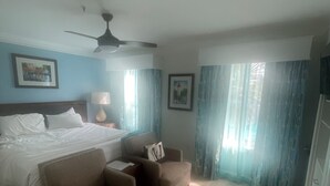 Ein Hotelzimmer mit Bett, Schreibtisch, Stuhl, Lampe und Deckenventilator.