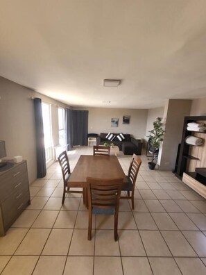 Un grand espace de vie comprenant une table à manger, des chaises, un canapé et un téléviseur.