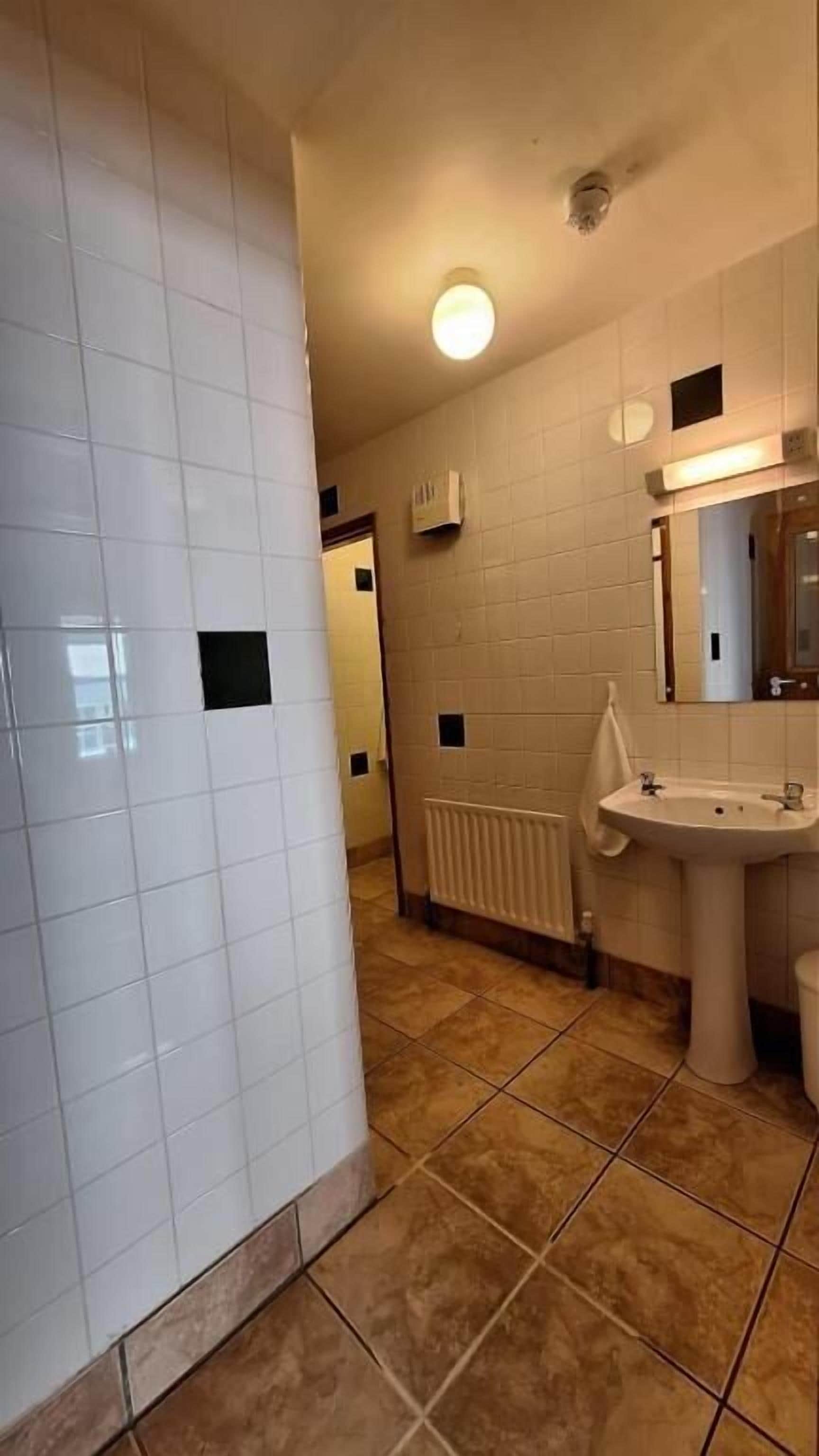 A bathroom with white tiled walls, a sink, and a mirror.