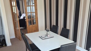 A dining area with a white table, black chairs, a wooden door, and striped wallpaper. - Delightful Ipswich Town 3 Bed House awaits you. (Ipswich)