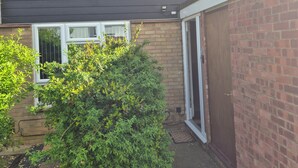 A two-story house with a dark exterior, a brick section on the right, and a small garden area with a bush. - Delightful Ipswich Town 3 Bed House awaits you. (Ipswich)