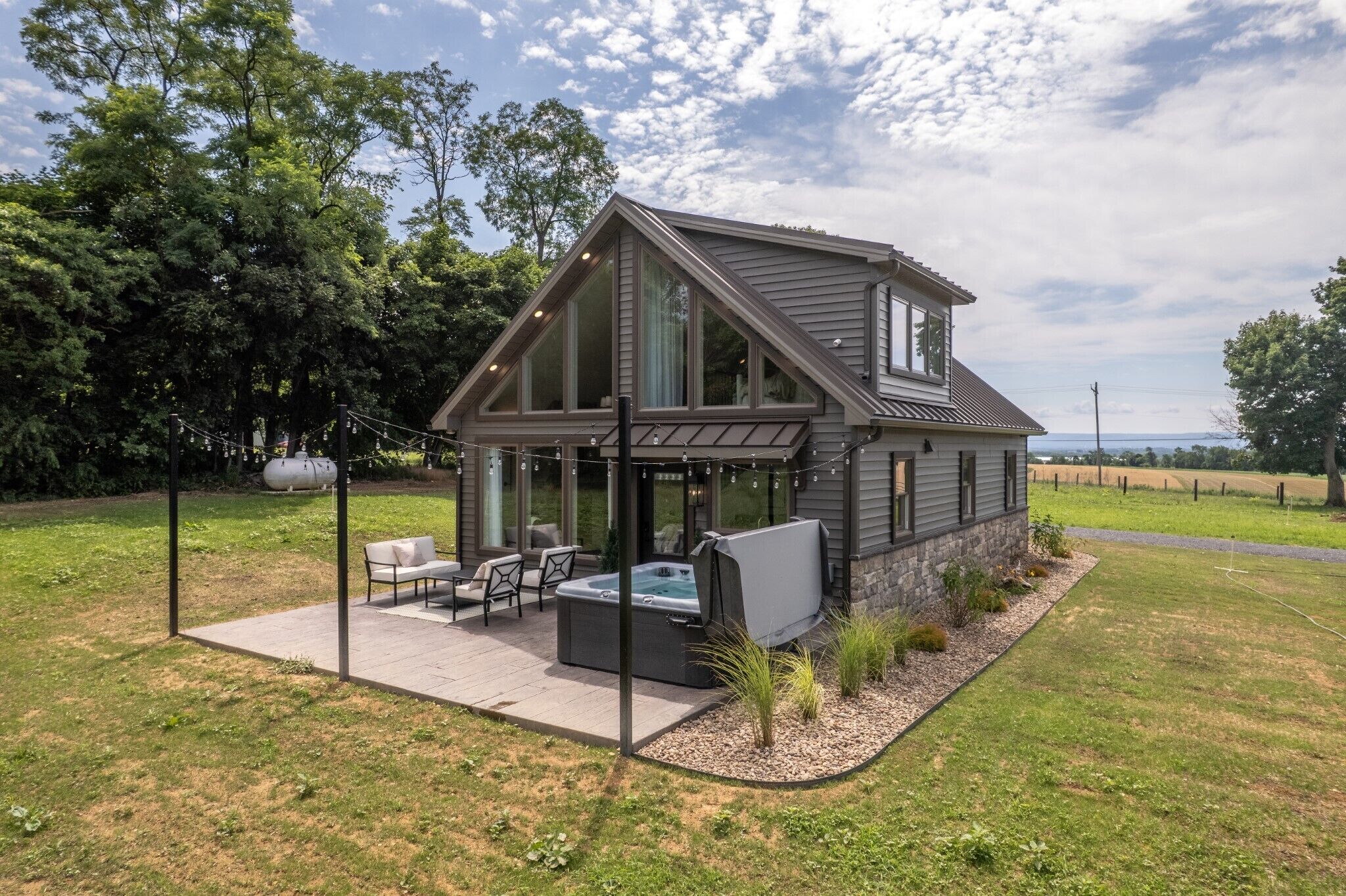 A modern house with a patio, hot tub, and a view of the countryside.