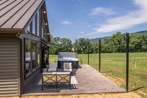 A patio with outdoor furniture, a hot tub, and a view of a green landscape. - Elm View Cottage in Newburg. A cozy 2 bedroom getaway. (Newburg)
