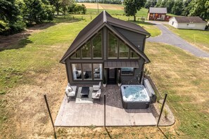 Ett modernt hus med en stor terrass, ett bubbelbad och utsikt över det omgivande landskapet.