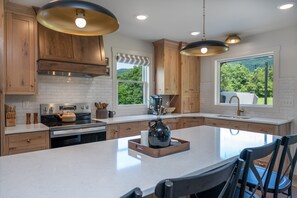 A modern kitchen with wooden cabinets, a large island, stainless steel appliances, and pendant lighting. - Elm View Cottage in Newburg. A cozy 2 bedroom getaway. (Newburg)