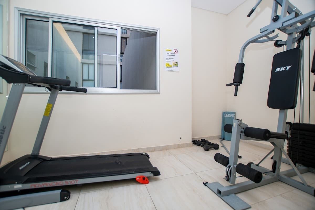 A gym with a treadmill, weight machines, and dumbbells.