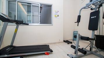 A gym with a treadmill, weight machines, and dumbbells.