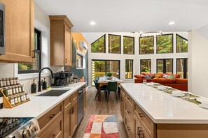 A modern kitchen with a dining area, large windows, and a view of the outdoors. - Pickleball Court, Hot Tub, Theatre, Secret Room! (Albrightsville)